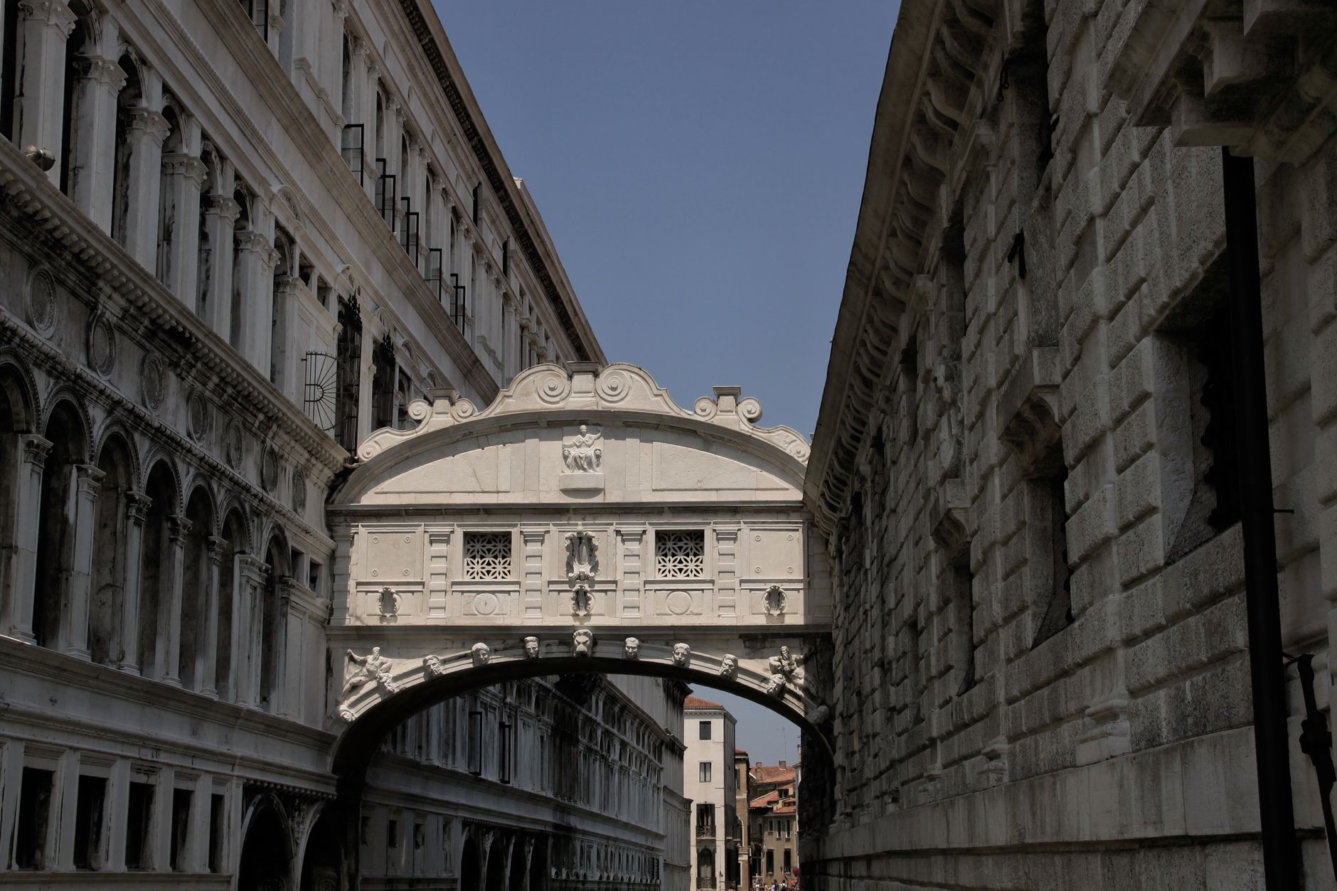 The iconic Bridge of Sighs connecting two historic Venetian buildings under the blue sky.