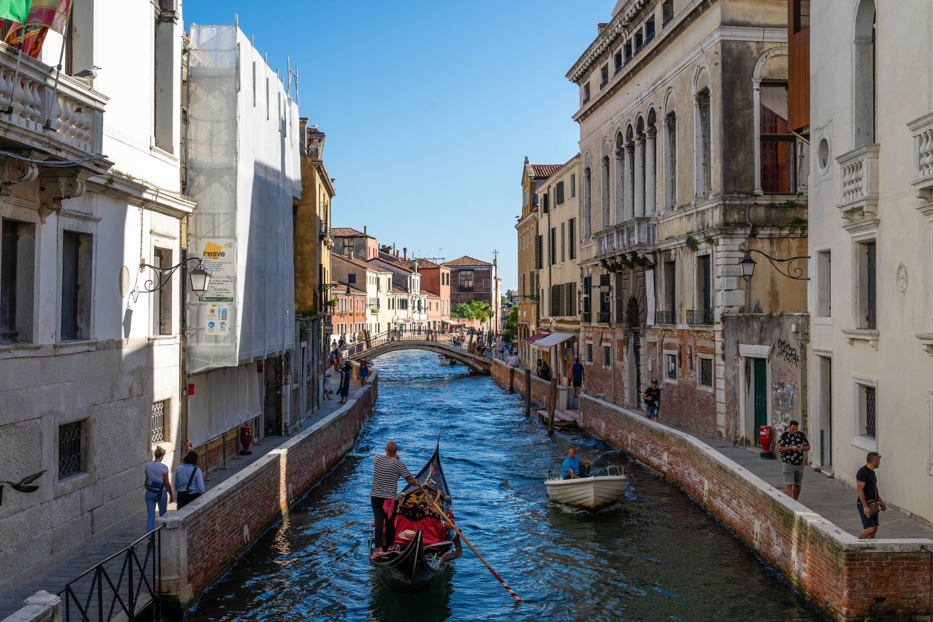 Scenic view of a gondola navigating a narrow canal in Venice, Italy, flanked by historic architecture.