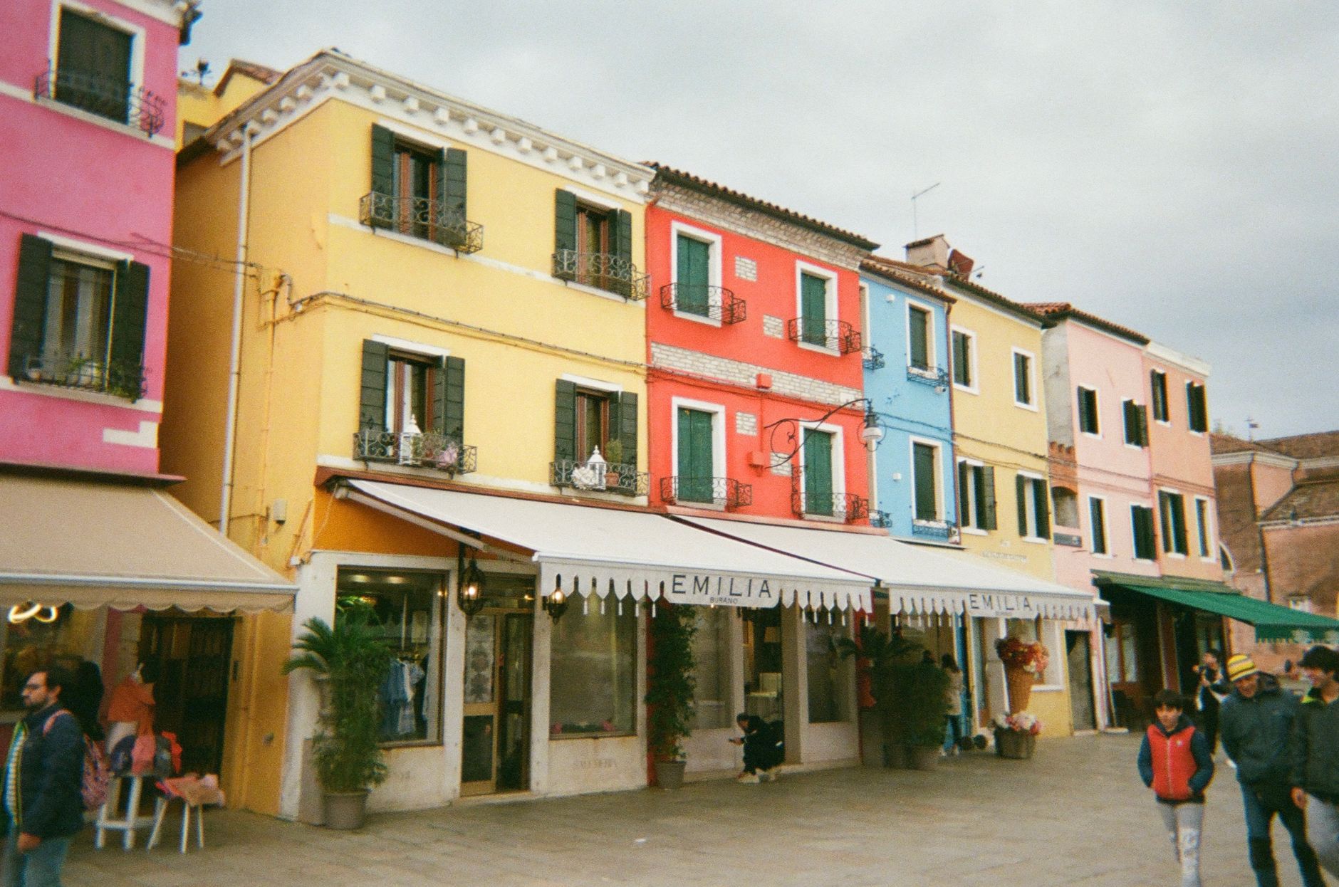 Vibrant houses line a street in Burano, showcasing the island's iconic colorful architecture.