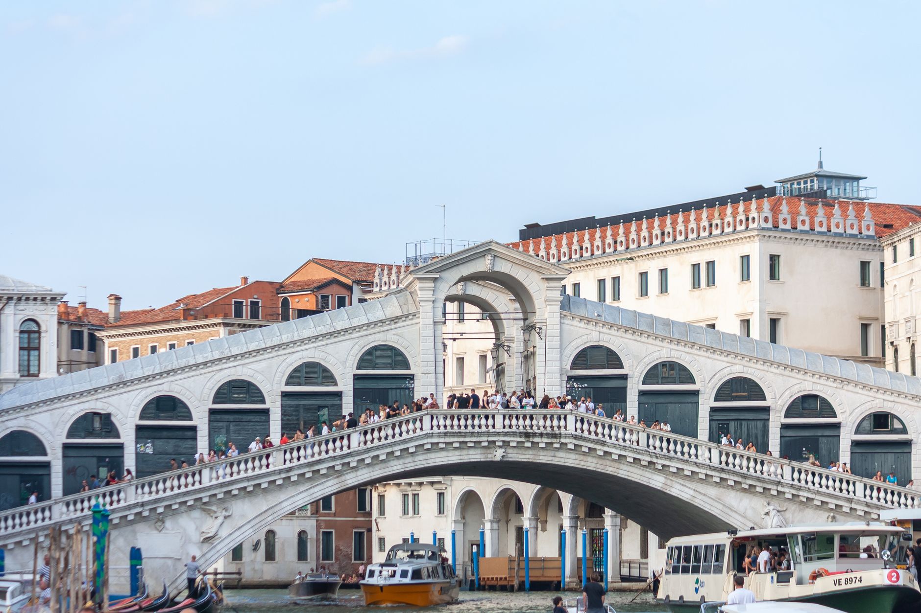 Iconic view of Venice's Rialto Bridge spanning the Grand Canal on a sunny day.